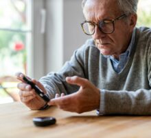 older man in sweater measures blood sugar to prevent diabetes
