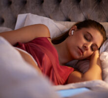 woman sleeping in bed with wireless earphones may hear unfamiliar voices