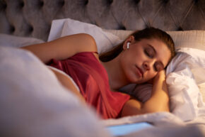 woman sleeping in bed with wireless earphones may hear unfamiliar voices